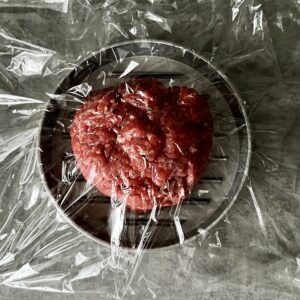 burger in burger press covered in clingfilm