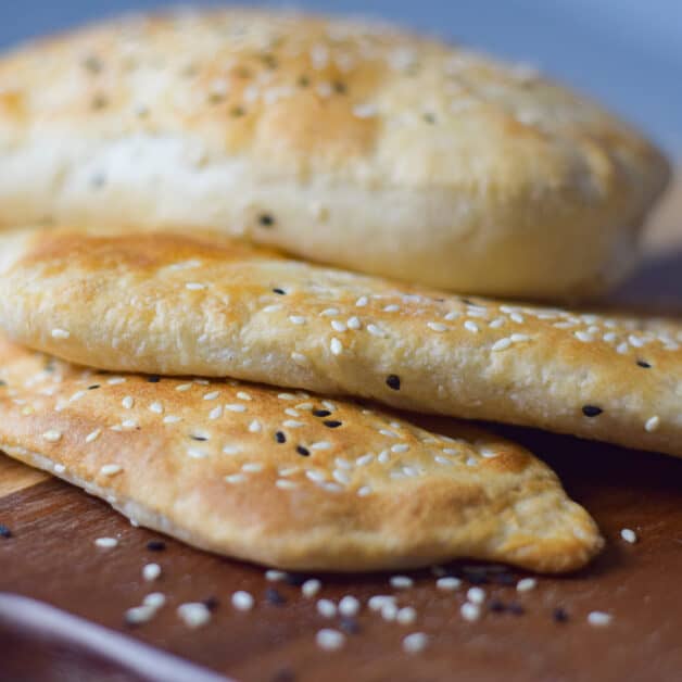 Shaobing Chinese bread with sesame seeds on a chopping board.