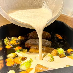easy toad in the hole with carrots and sprouts pouring batter
