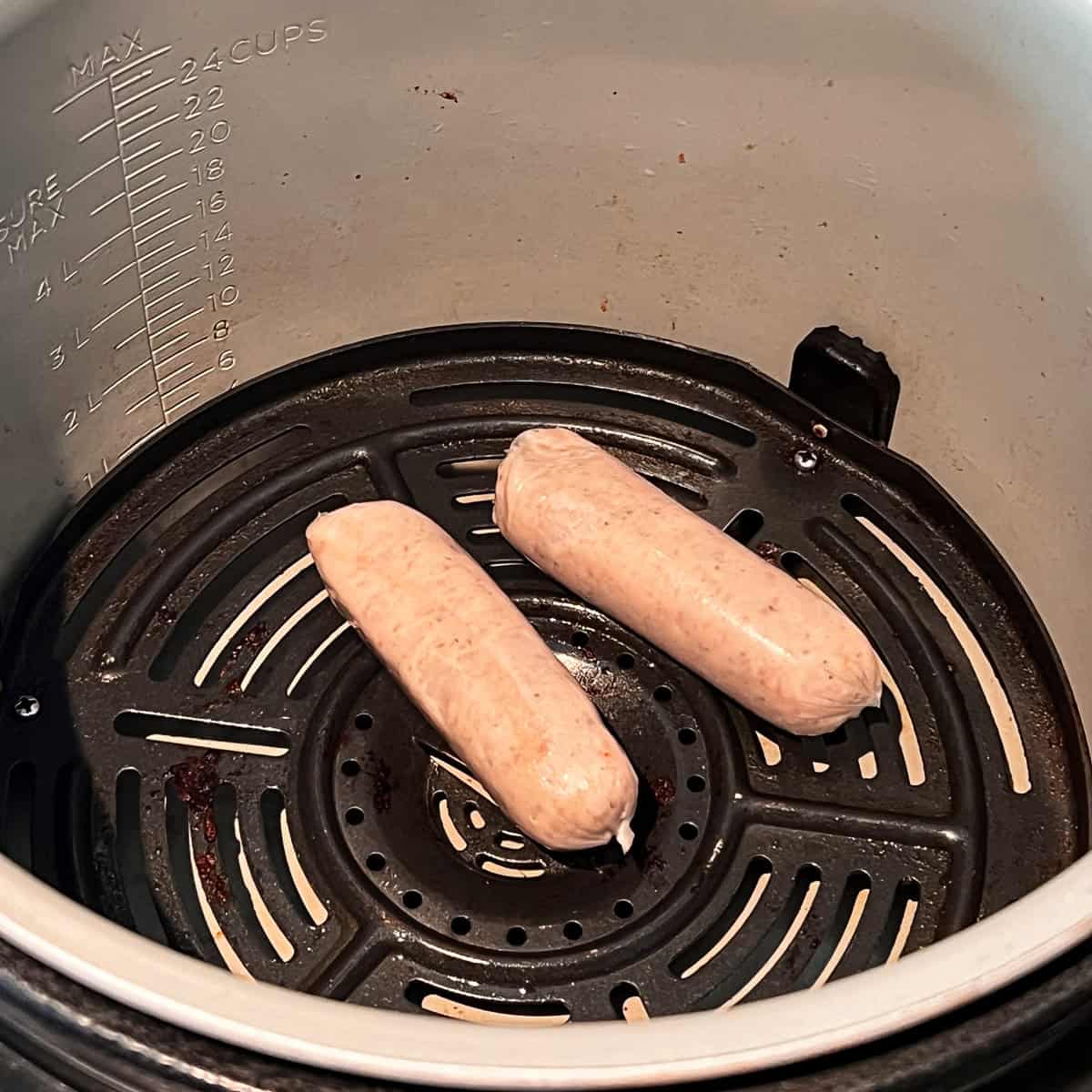 Two raw sausages in an air fryer.
