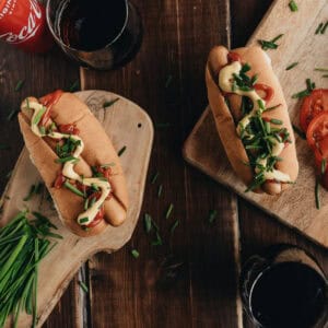 Two hot dogs with mayo on wooden serving boards.