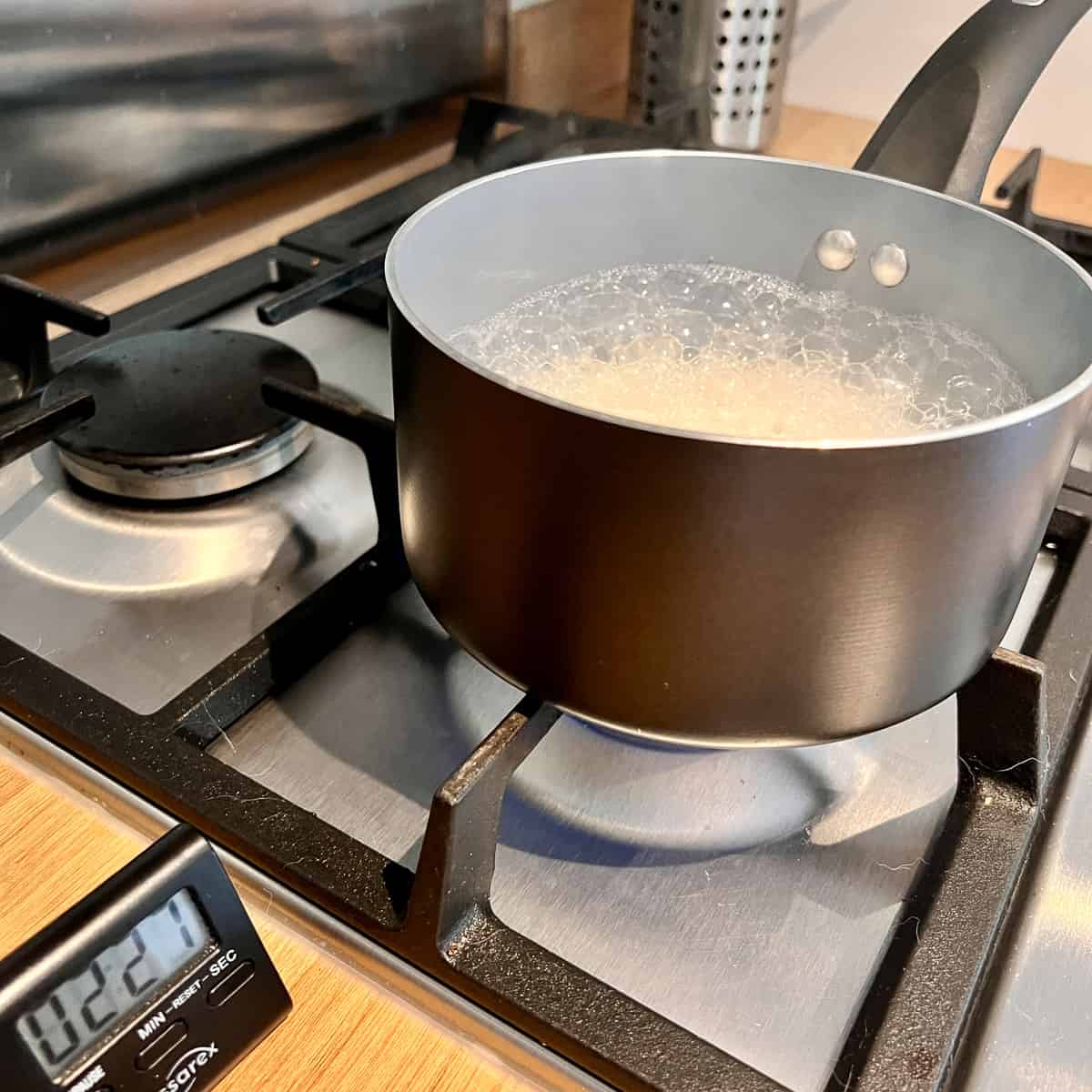 Rice boiling in a pan with a kitchen timer.