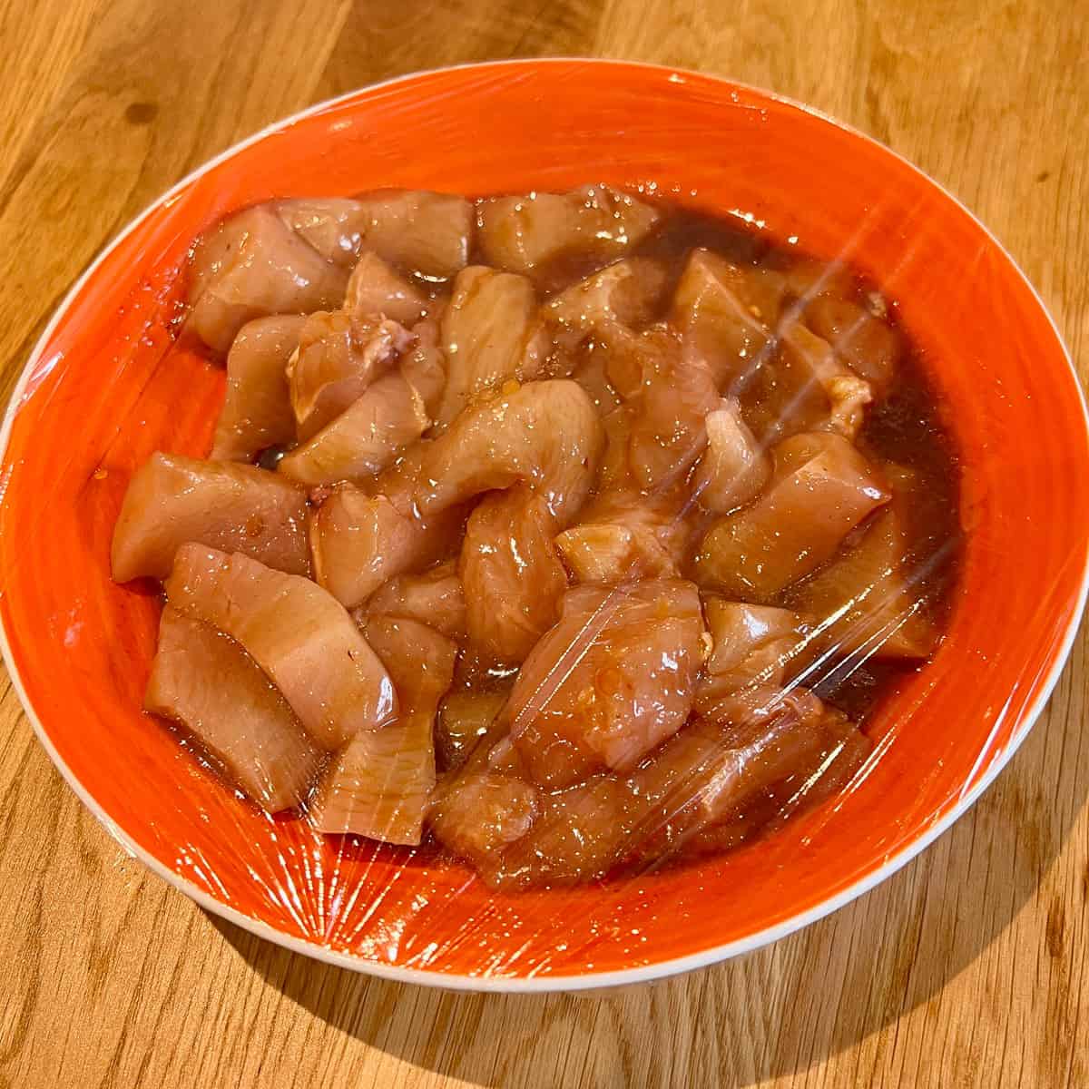 Raw chicken marinate covered in cling film.