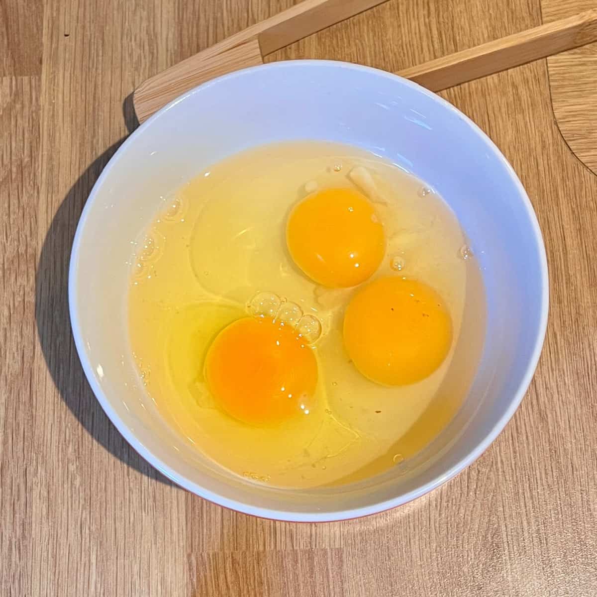 Three eggs cracked in a bowl.