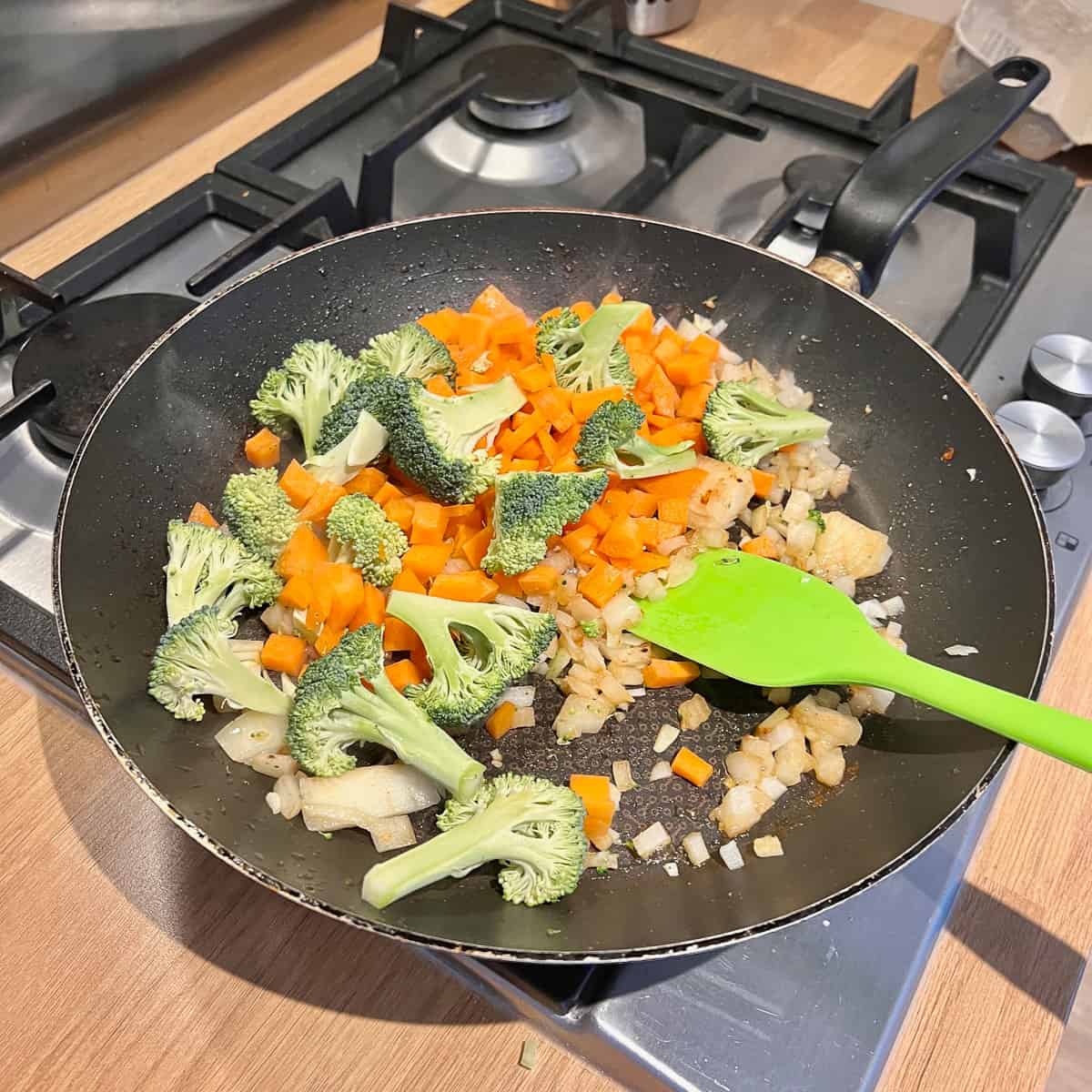 Broccoli, carrots, onion and garlic in a frying pan.