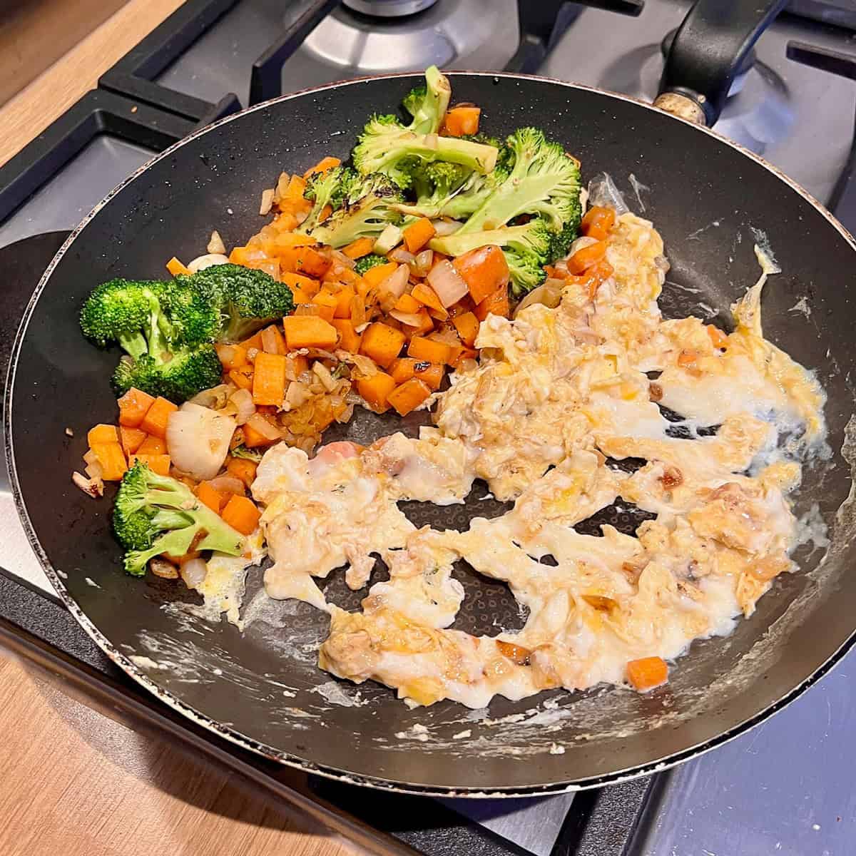 Broccoli, carrots, onion and garlic in a frying pan with egg.