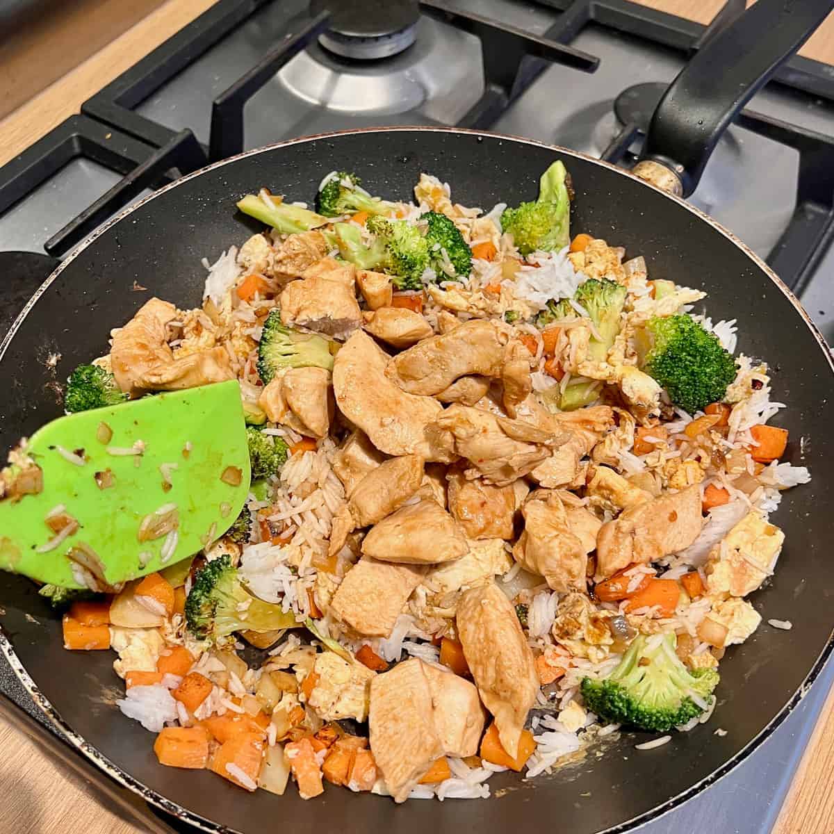 Chicken, soy, broccoli, carrots, onion and garlic in a frying pan.