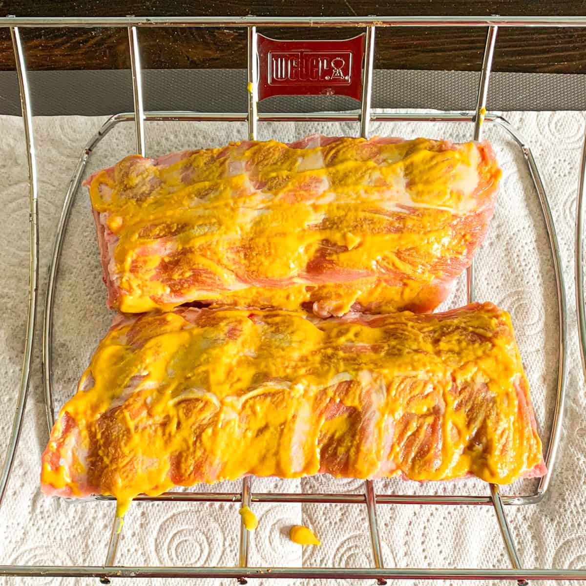 Raw rack of ribs covered with mustard.