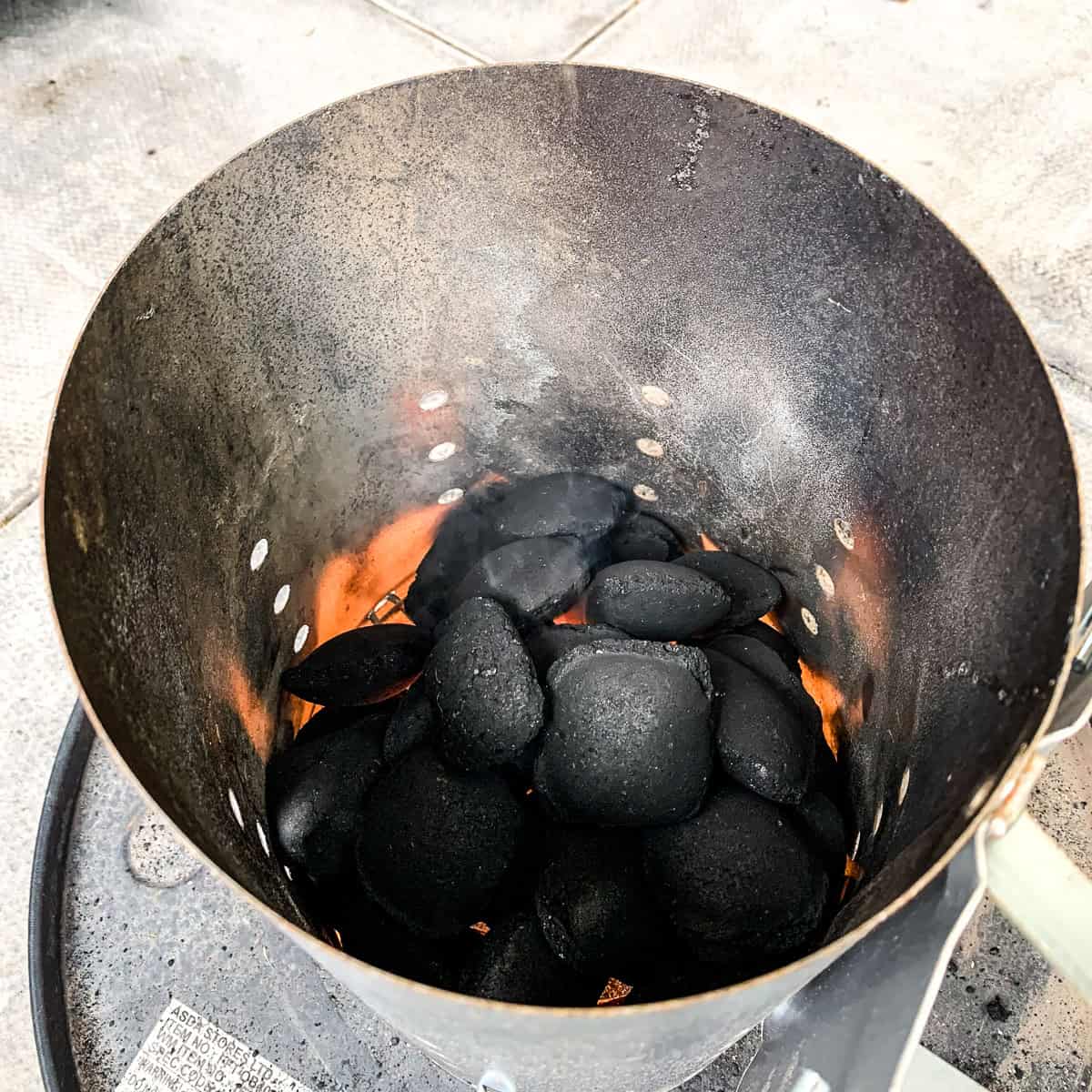 Charcoal lit in a Weber chimney starter.