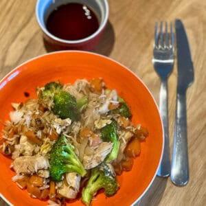 Dish of chicken and vegetables on a plate with a knife and fork.
