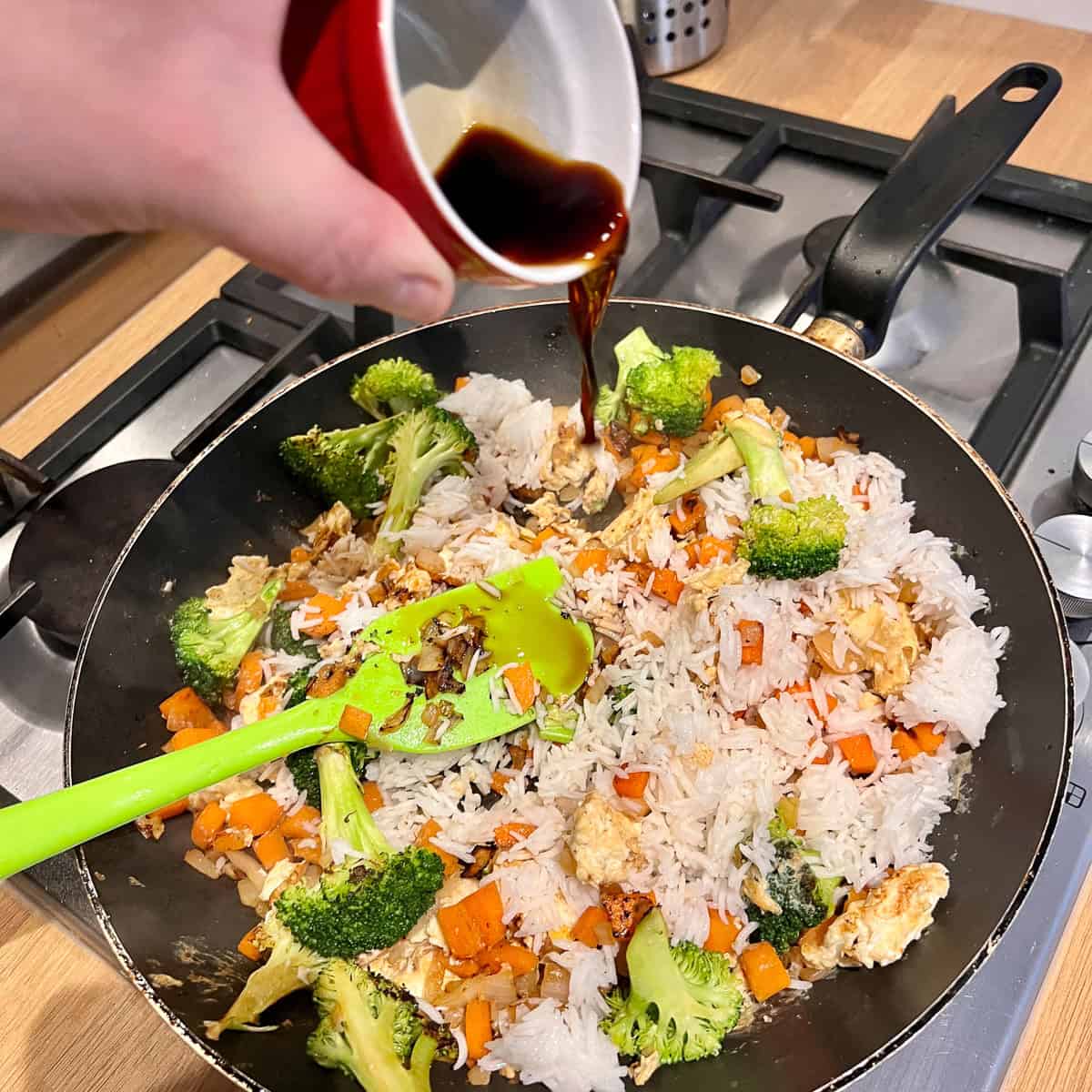 Pouring soy sauce in a frying pan of stir fry.