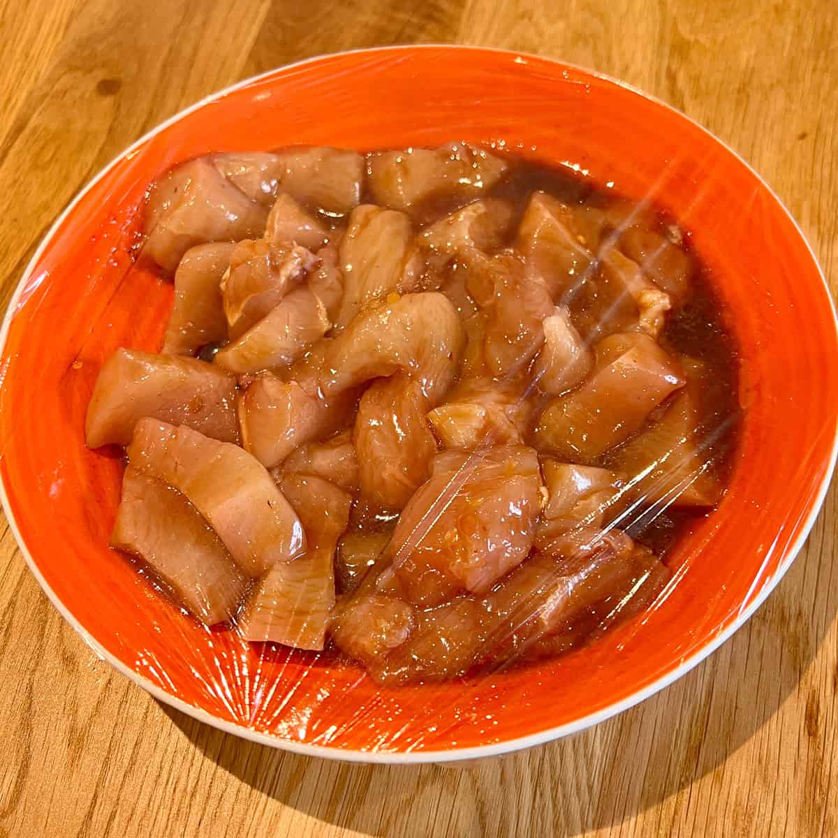 Chicken pieces marinating in a bowl.