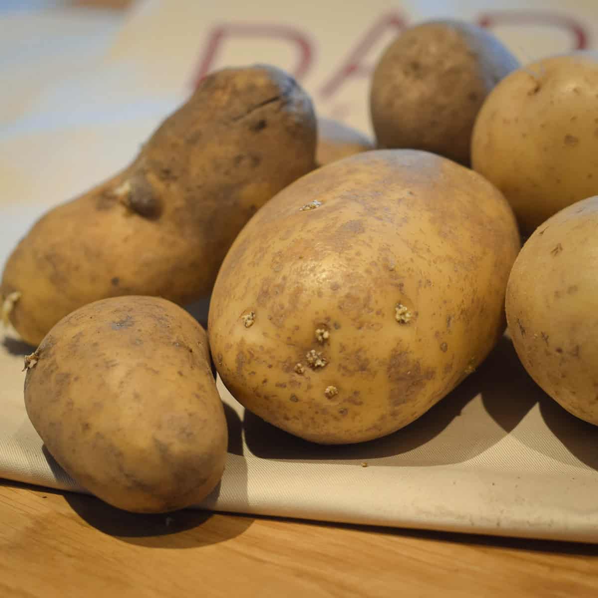A few potatoes of various sizes on a table.