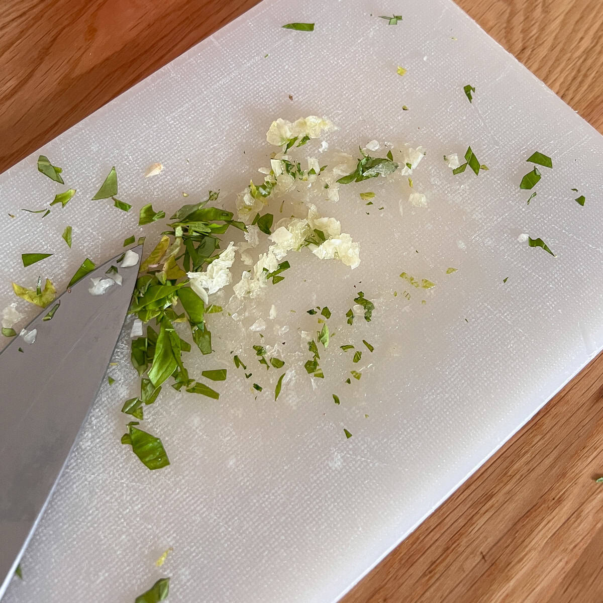 Chopped garlic and herbs on a chopping board.
