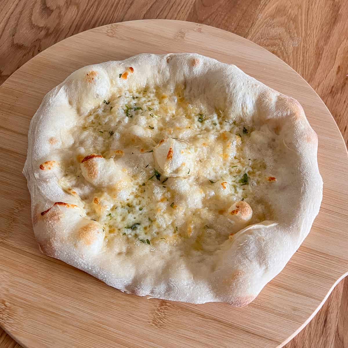 Garlic and cheese pizza bread on chopping board.