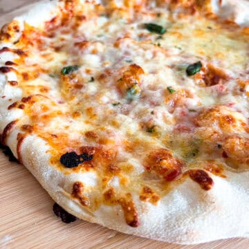 Close up of margherita pizza on chopping board.
