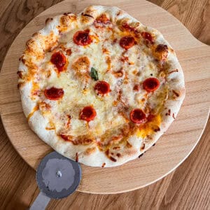 Nduja stuffed tomato pizza on chopping board.