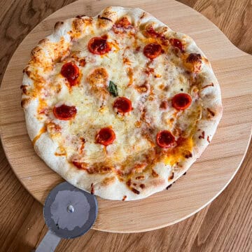 Nduja stuffed tomato pizza on chopping board.
