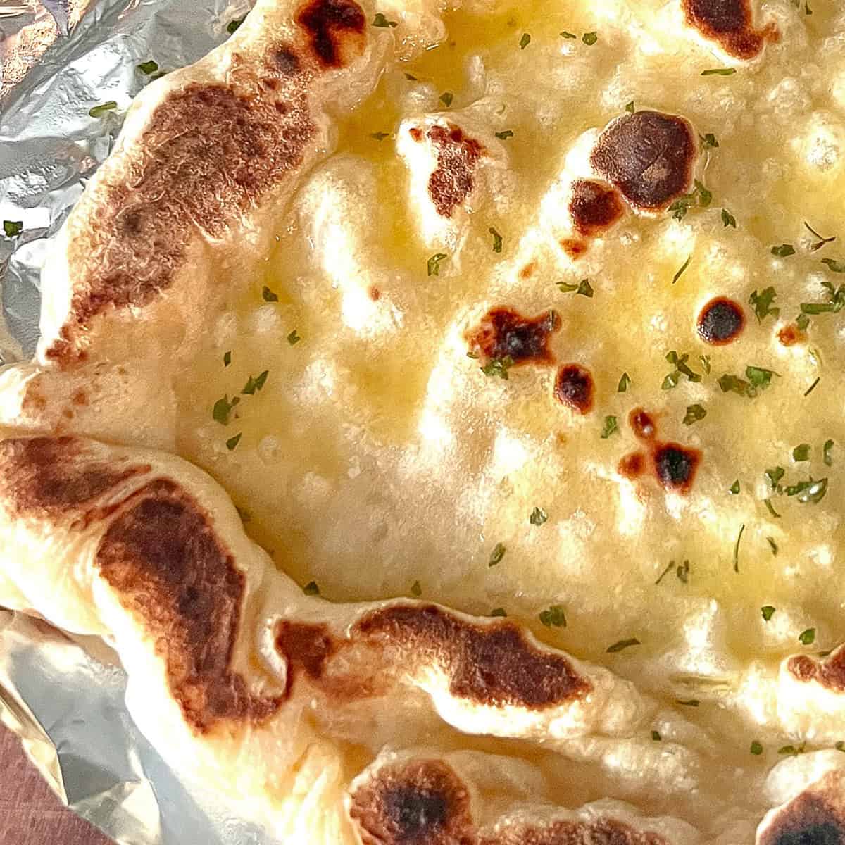 Naan bread on foil with garlic butter.