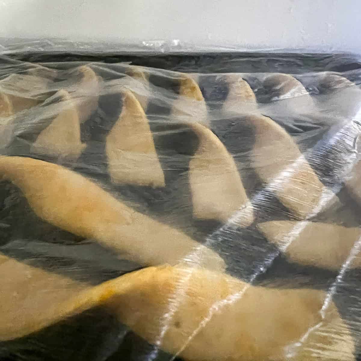 Cheese straws covered in cling film in the fridge.