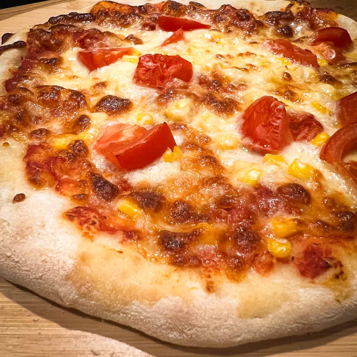 Close up of a cheese, tomato and sweetcorn sourdough pizza.