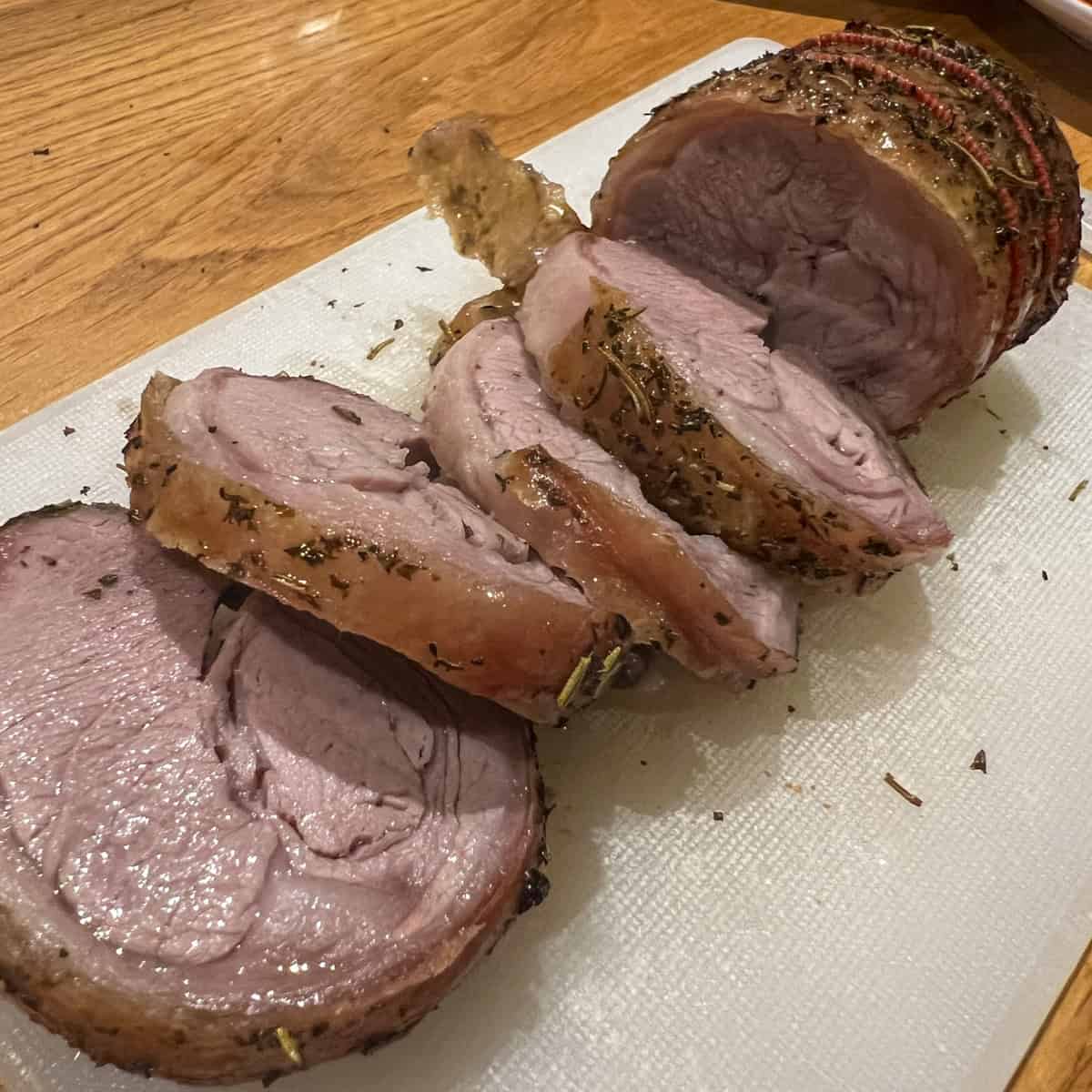 Sliced roast lamb on a chopping board.