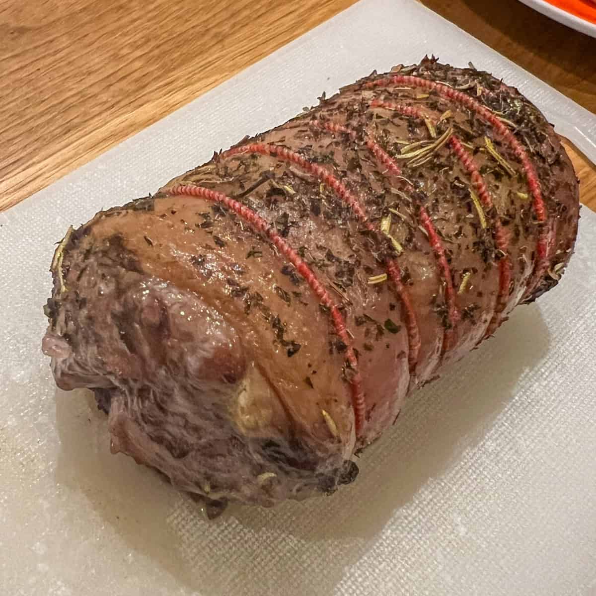 Prepped lamb coated with rosemary and mint ready for roasting.
