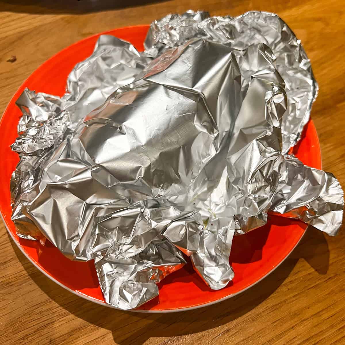 Wrap roast lamb resting on a plate.