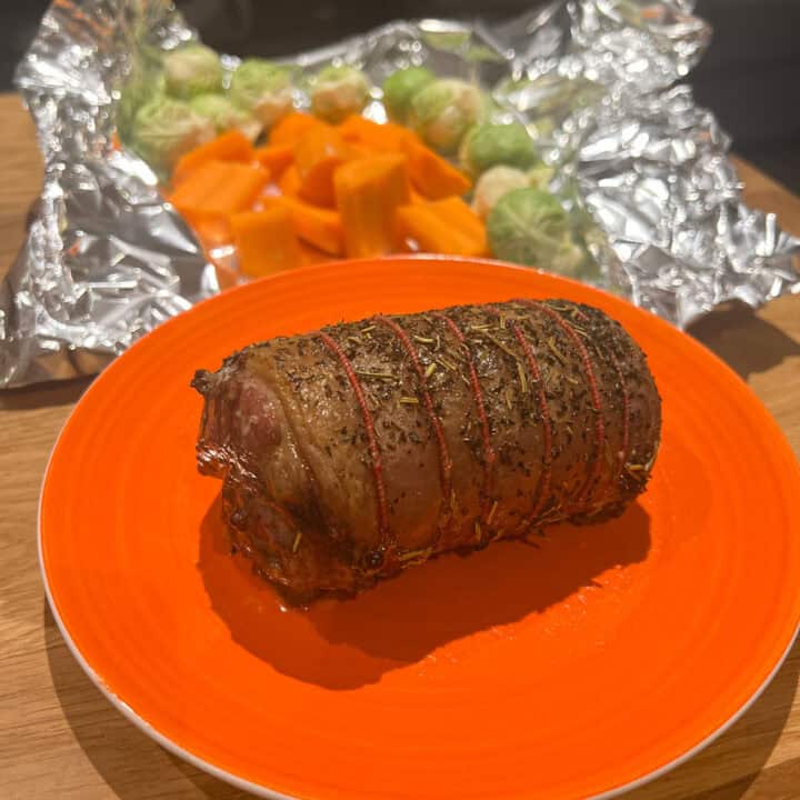 Roast lamb cooked and resting on a plate.