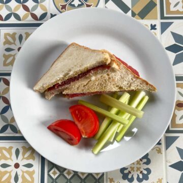 Image of a Pastrami and mustard sandwich on a plate on a table.