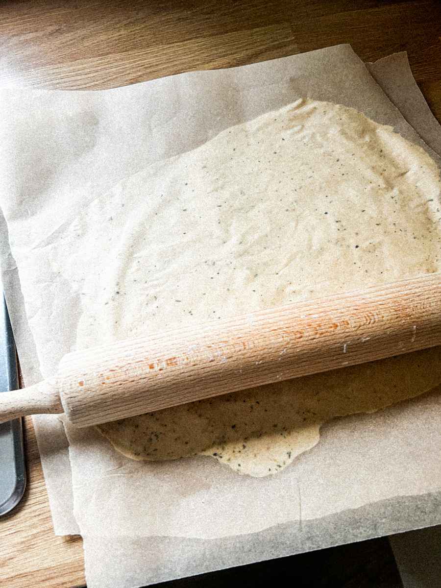 Rolling out the sourdough discard between baking sheets.