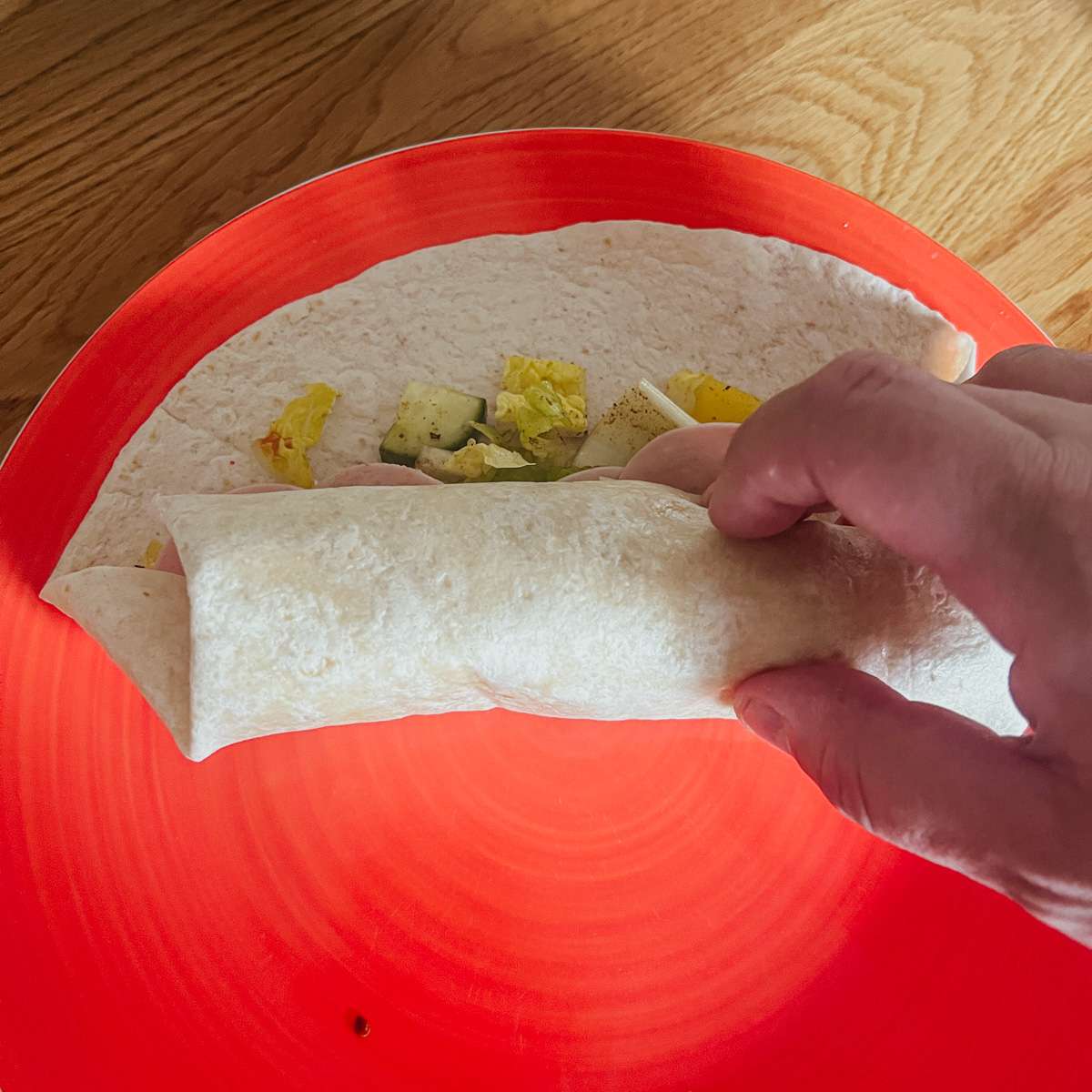 Folding over tortilla to make wrap.
