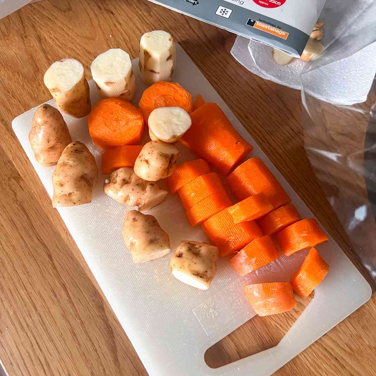 Chopped potatoes and carrots on chopping board.