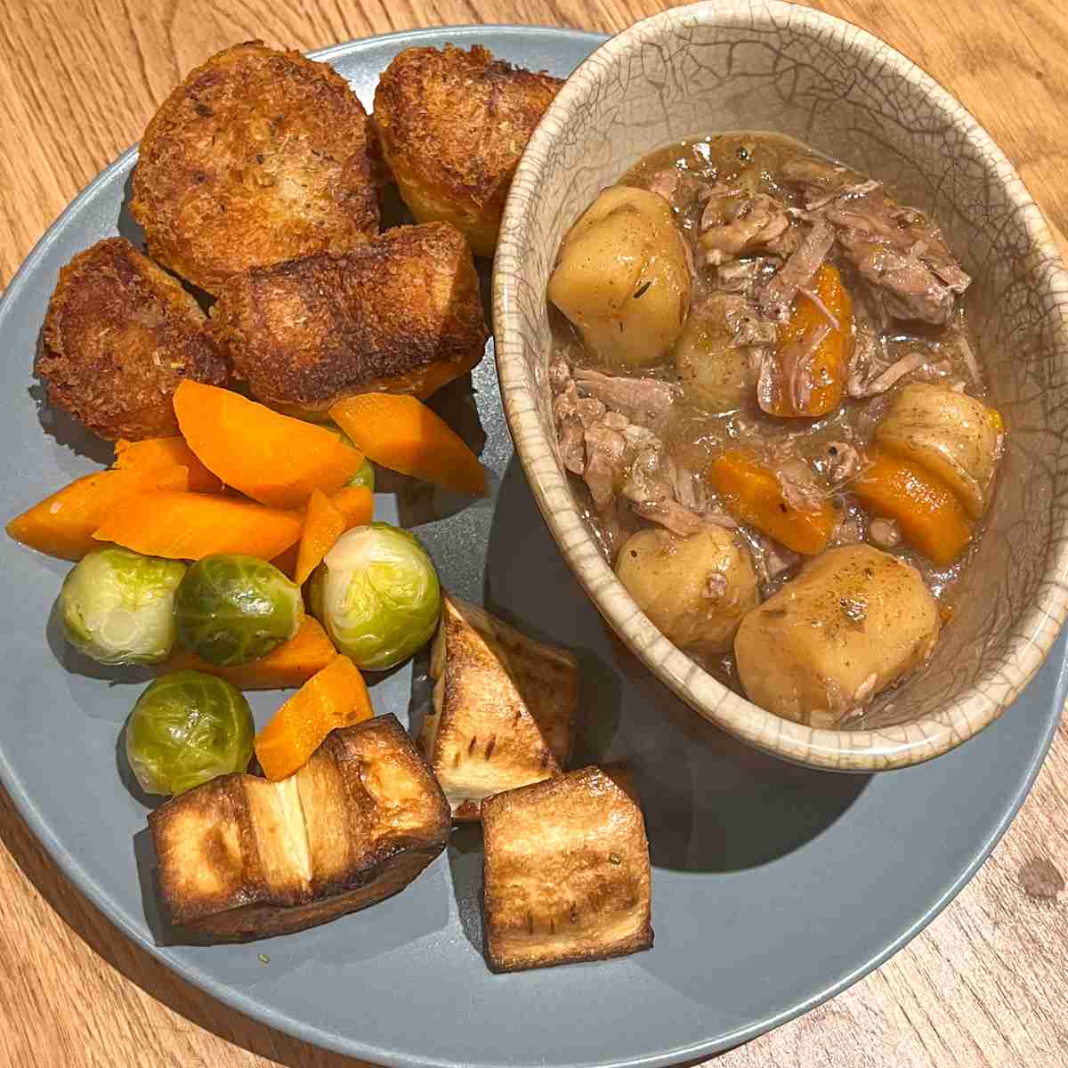 Lamb stew on plate with roast dinner.