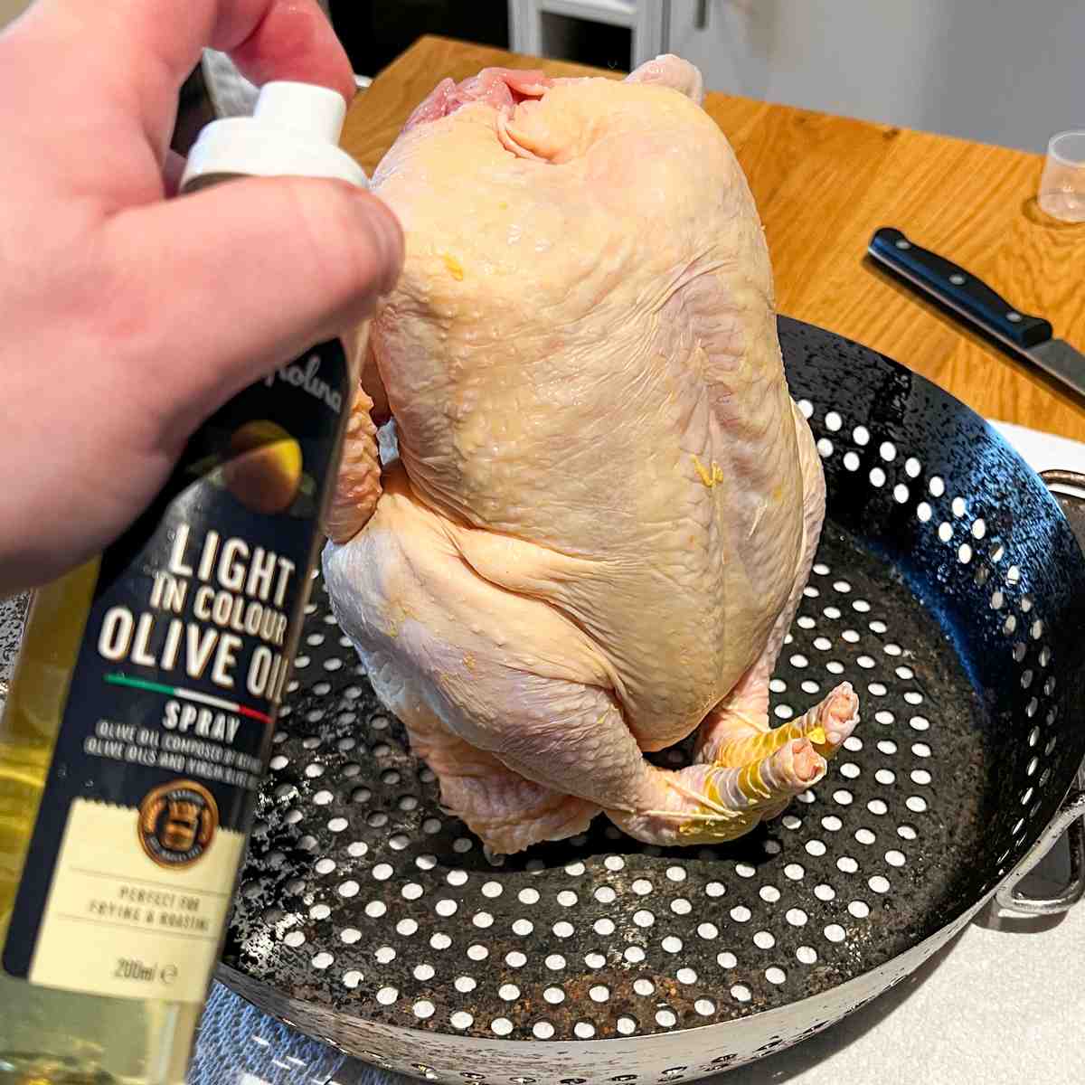 Spraying olive oil on Lemon Herbert BBQ Beer Can Chicken
