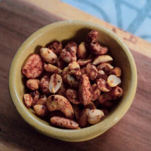 A bowl of spicy honey nuts featuring chili flakes, cumin, and a honey glaze, perfect for snacking.