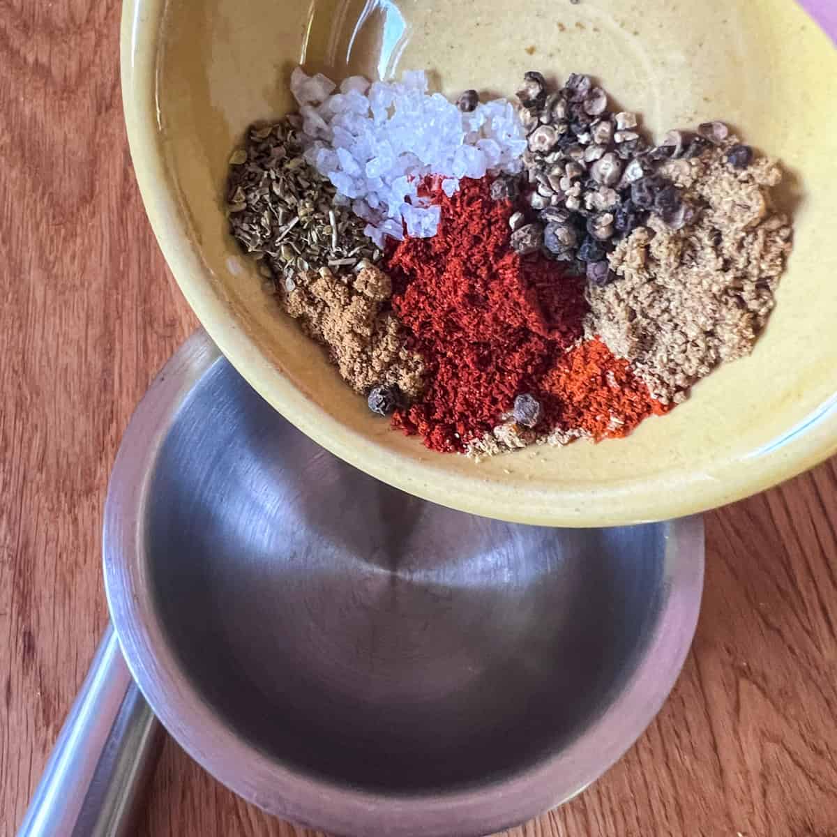 Seasonings being poured into a pestle and mortar ready to mix.