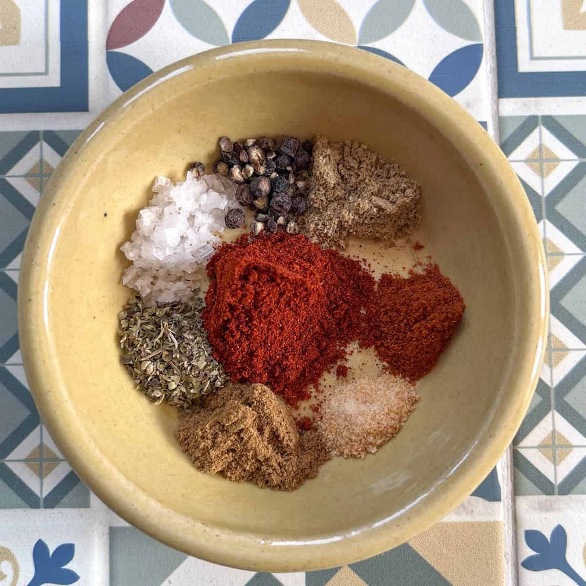 8 seasonings in a yellow dish on a tile table.