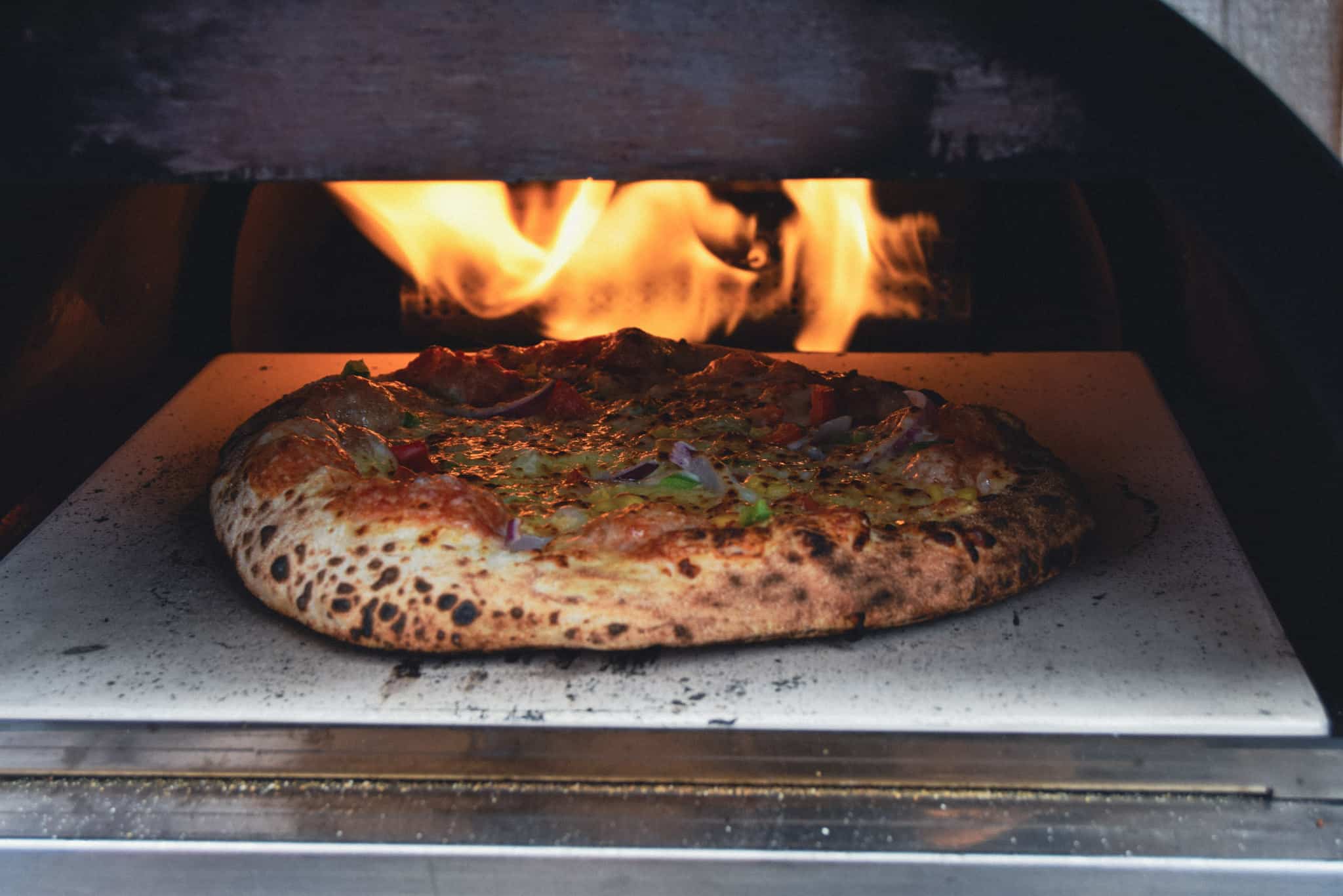Pizza on pizza stone baking in oven.
