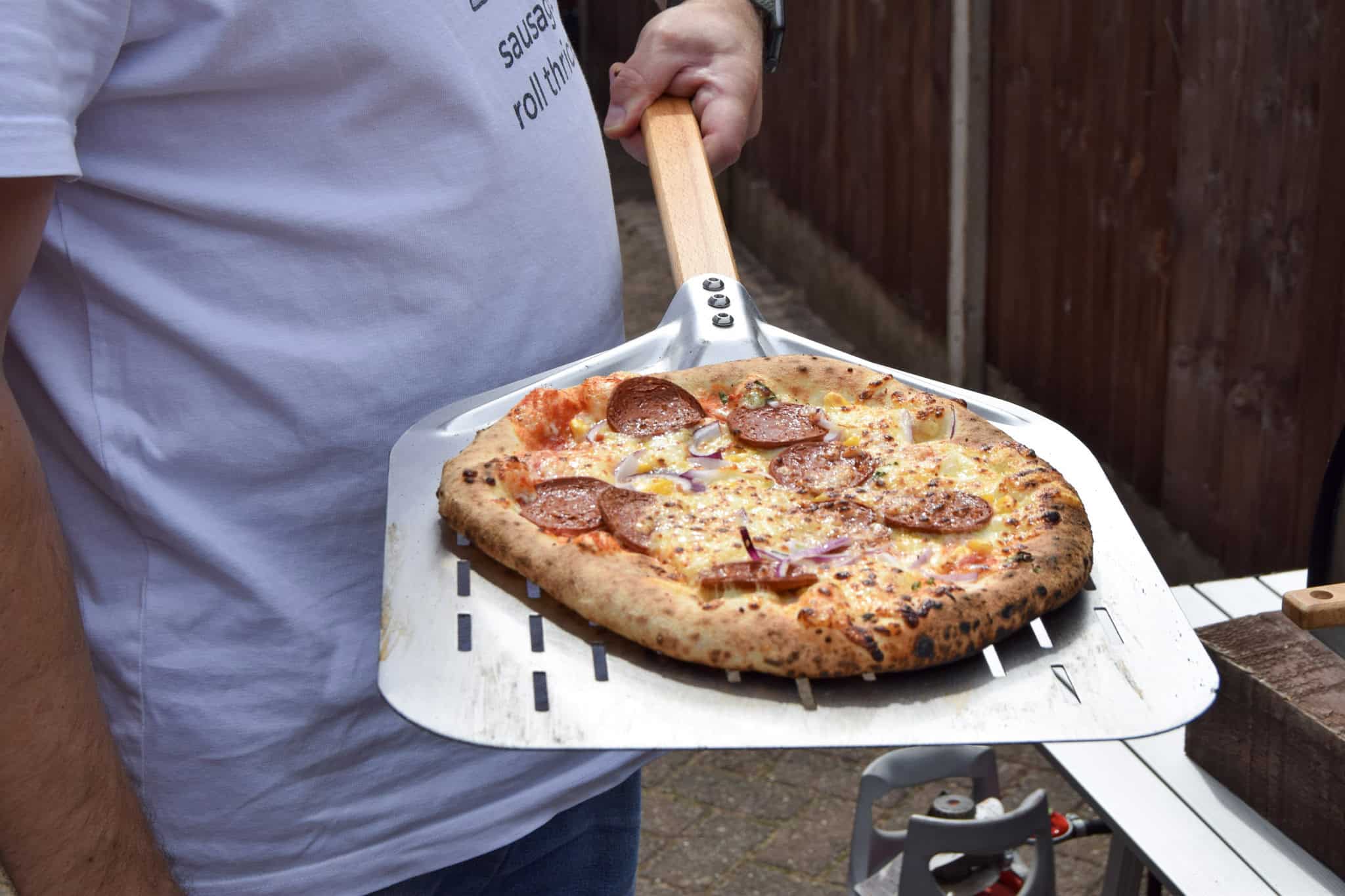 Pizza freshly cooked on a pizza peel.
